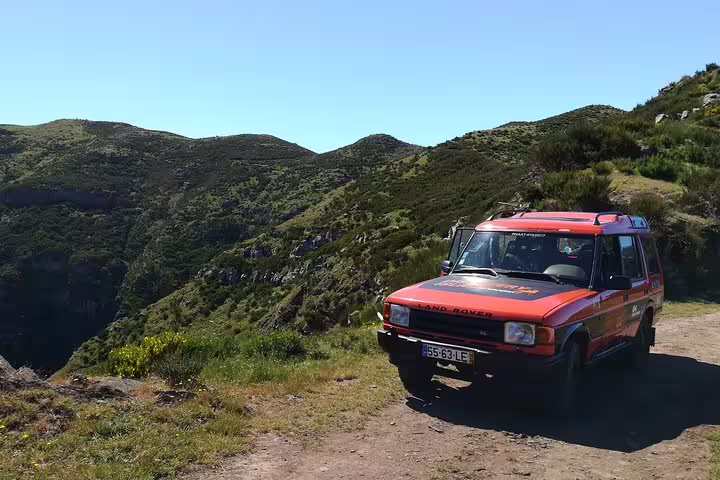 A Jeep parked on a scenic hillside in Câmara de Lobos, offering breathtaking views of Madeira's lush landscapes.