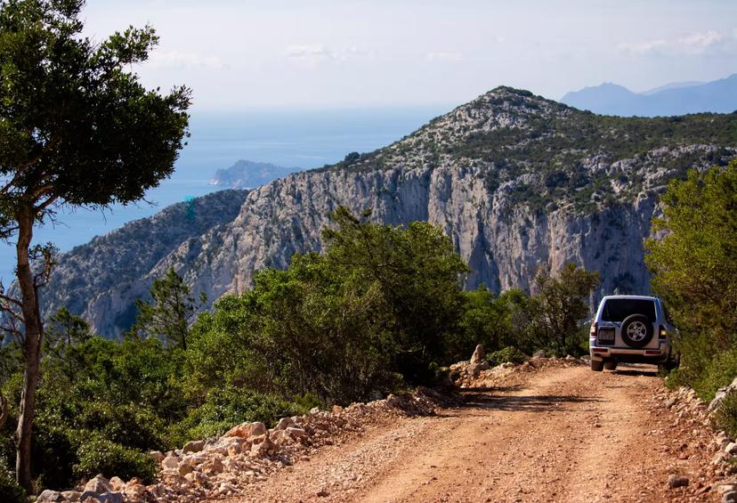 Jeep navigating a dirt road with stunning views of cliffs and sea on the Golgo Plateau tour from Arbatax.