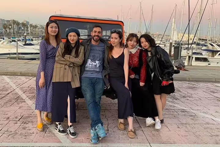 Group of friends poses with a Jeep by the Cascais marina, capturing memories of their Sintra-Cascais adventure.