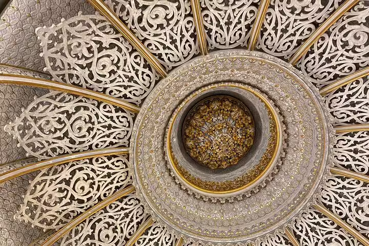 Intricate Moorish-style ceiling in Sintra's Monserrate Palace, showcasing detailed carvings and ornate design.