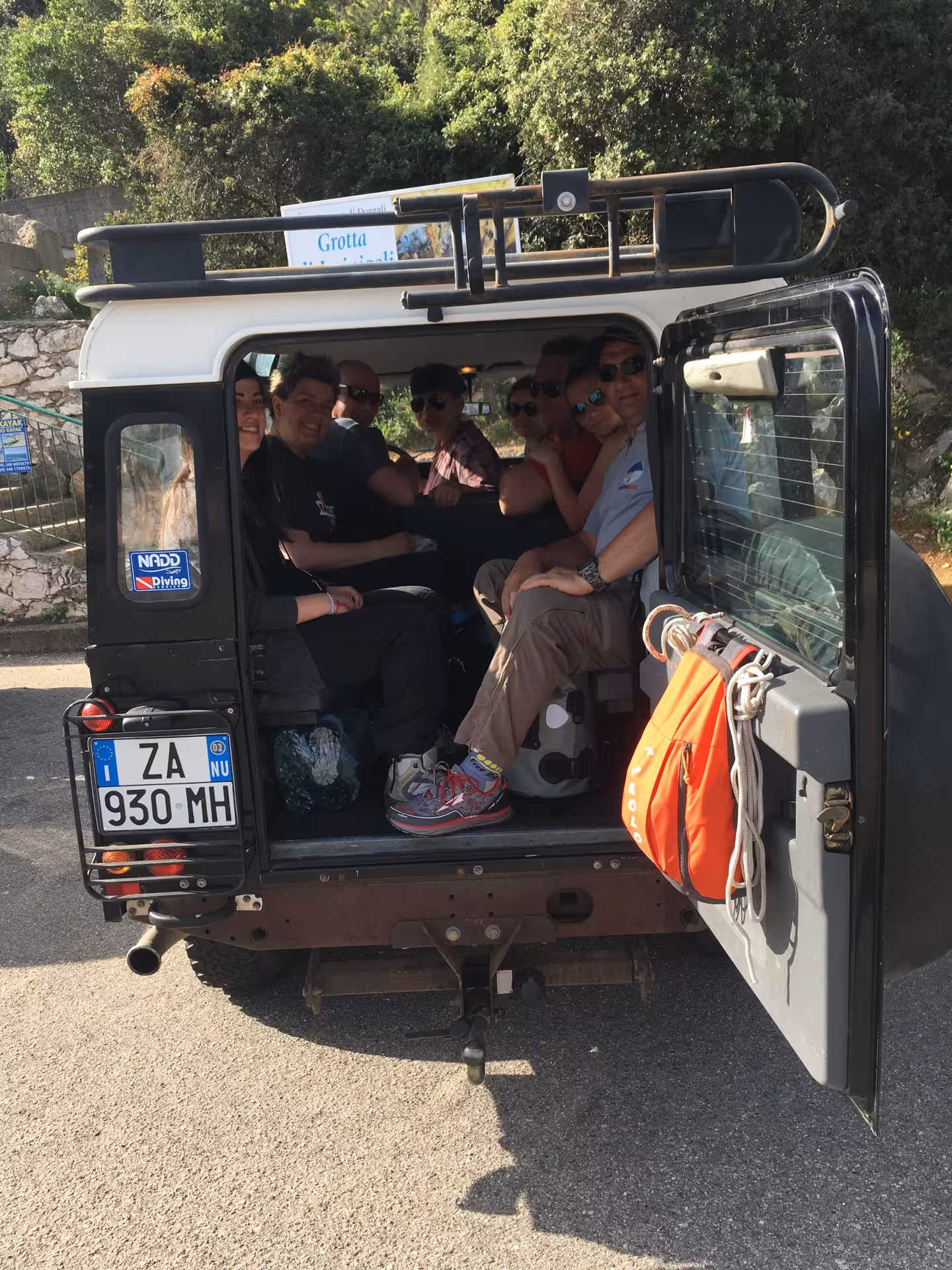 Group of tourists smiling inside a Jeep ready for a Supramonte adventure from Cala Gonone.
