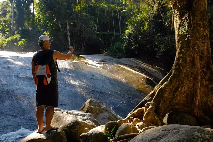 Man captures stunning waterfall view on Jeep tour adventure through scenic forest trails.