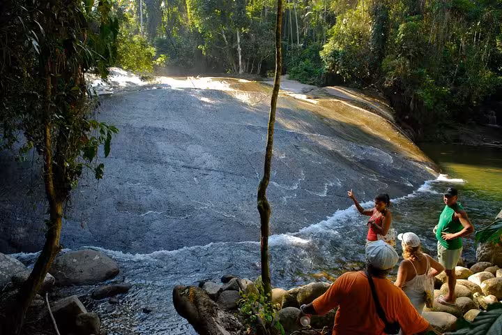 Tourists exploring serene waterfall area during a lush jungle Jeep tour, ideal for adventure seekers and nature lovers.