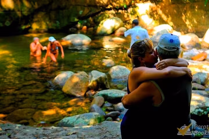 Visitors enjoying a refreshing swim and relaxation in a natural pool surrounded by rocks during a scenic Jeep tour.