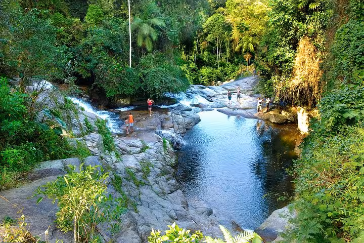 Scenic view of a tranquil waterfall and natural pool surrounded by lush greenery on a Jeep tour adventure.