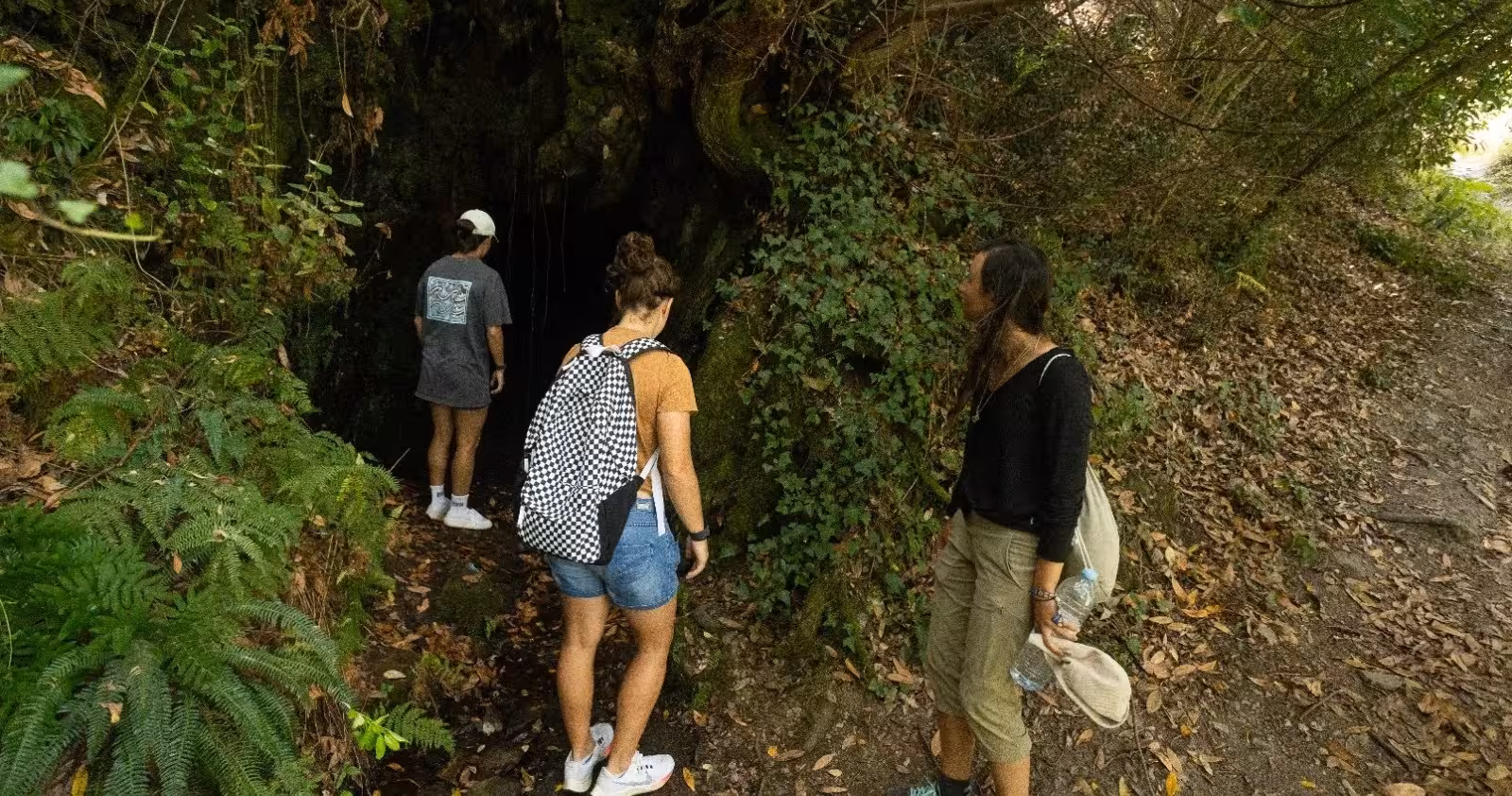 Guests explore a mossy cave entrance during the Jeeptour nature hike and yoga class, vintage car tour