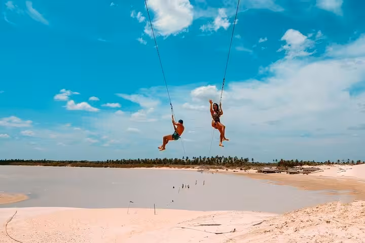 Travelers on a dune swing over Lagoa do Paraíso on the Jericoacoara West Coast tour in Ceará, Brazil