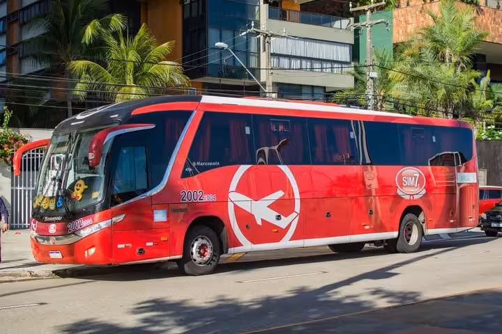Red tourist coach on city street for Jericoacoara to Fortaleza transfer, reliable shared shuttle in Ceará