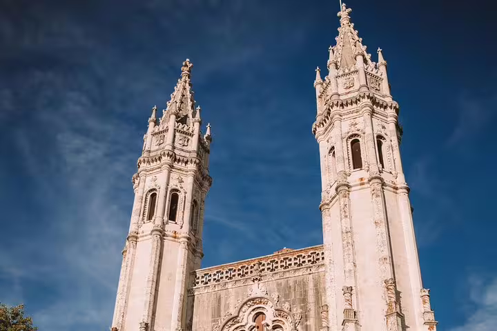 Stunning view of the ornate towers of Jerónimos Monastery under a clear blue sky in Belém, Lisbon.