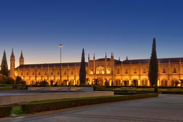 Illuminated Jerónimos Monastery in Lisbon at twilight, showcasing Gothic architecture on a private Sintra and Lisbon tour.