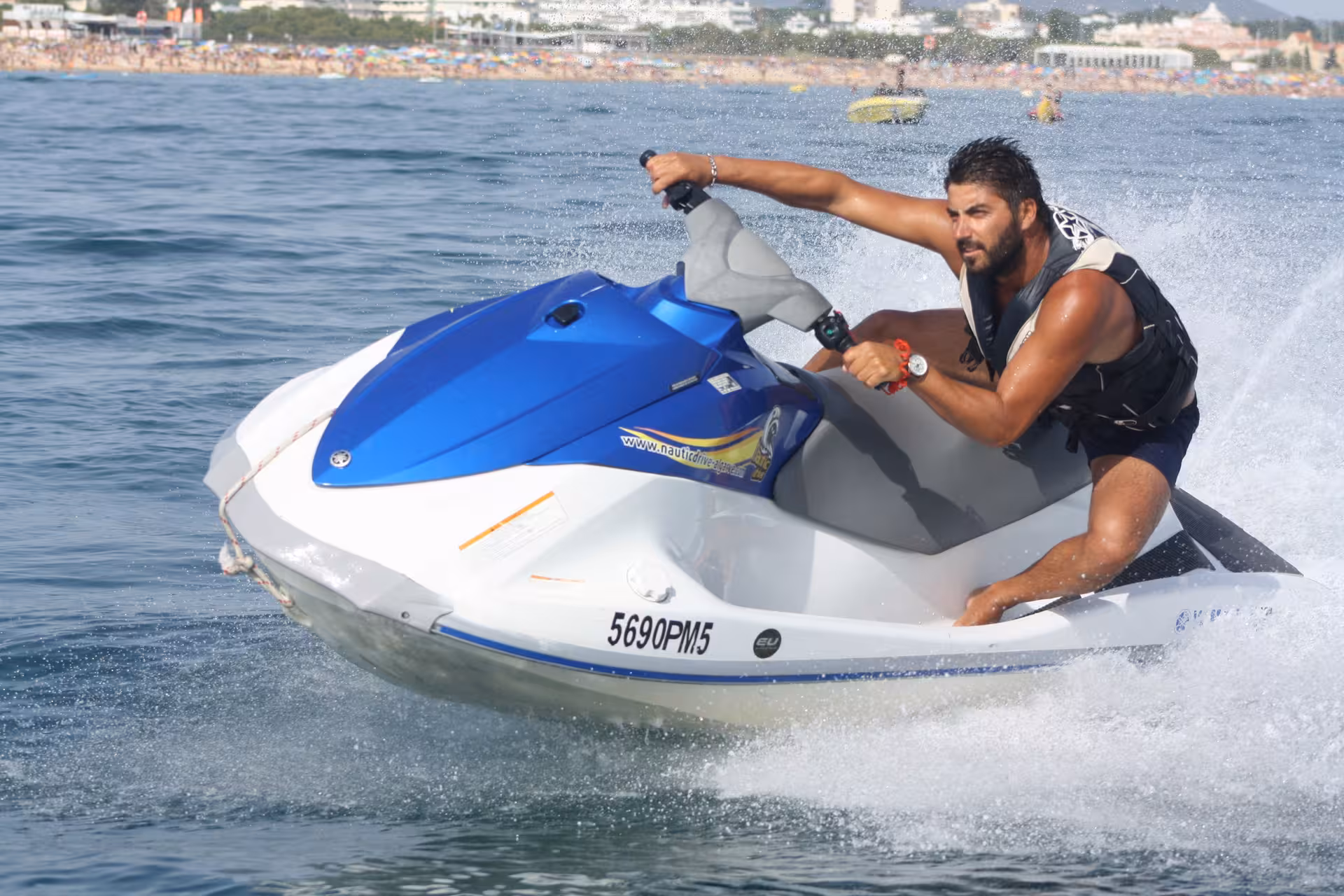 Focused rider carving waves on a blue jet ski near Praia da Rocha Baixinha, showcasing Algarve water sports fun