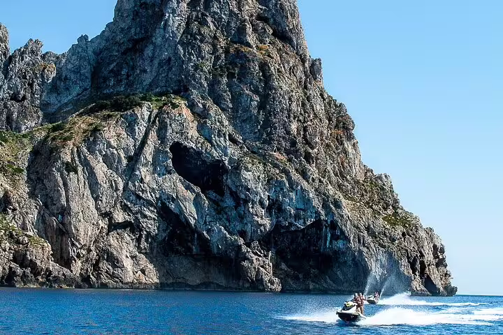 Jet ski tour from San Antonio Ibiza speeding past Es Vedrà cliffs, ocean spray on a sunny day