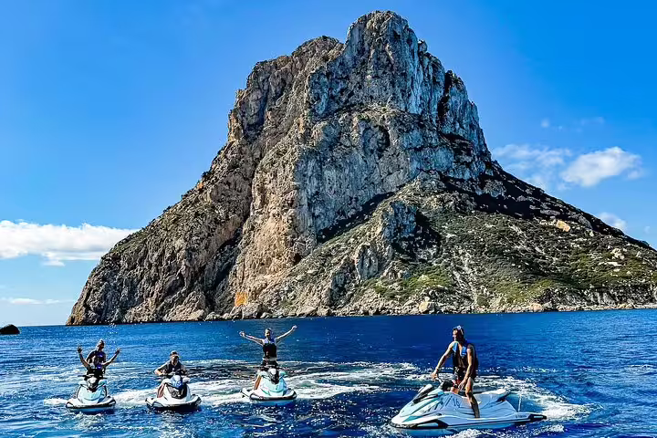 Jet ski tour from San Antonio Ibiza to Es Vedrà, riders posing on crystal-blue sea by the iconic rock