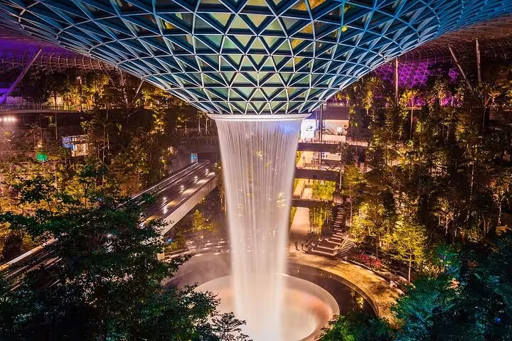 HSBC Rain Vortex waterfall at Jewel Changi Airport Canopy Park, glowing indoor forest at night