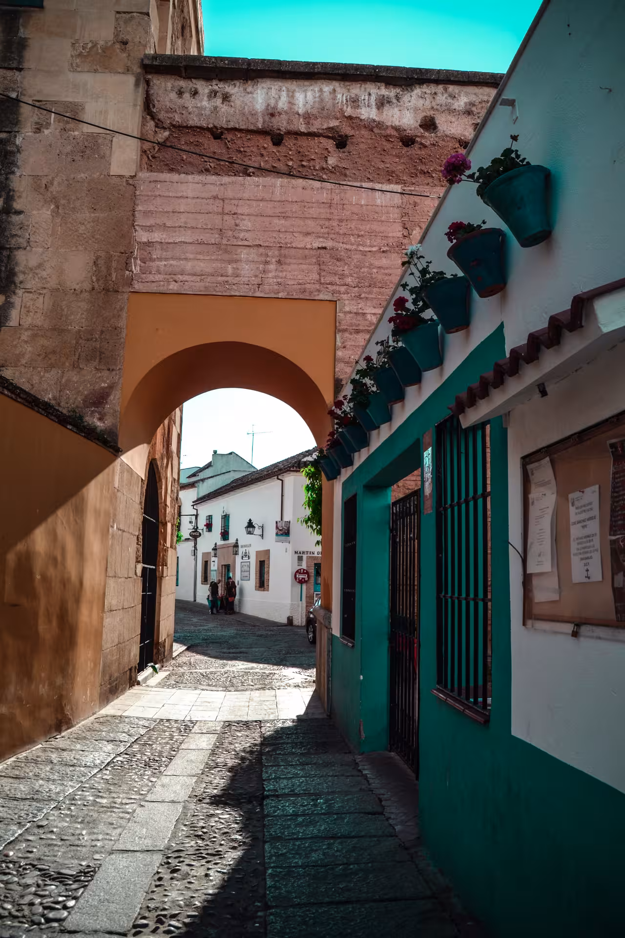 Picturesque alleyway with an arch and flower pots in the Jewish Quarter, highlighting Andalusian charm.