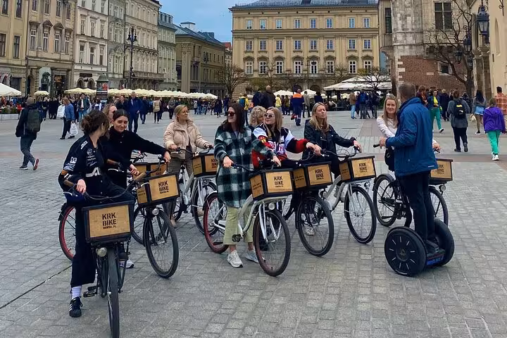 Cyclists gather with a guide on a segway in a historic square, starting a cultural bike tour in the Jewish Quarter.