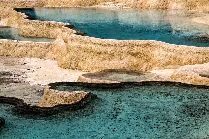 Close-up of Jiuzhaigou's unique terraced limestone formations filled with clear blue water.