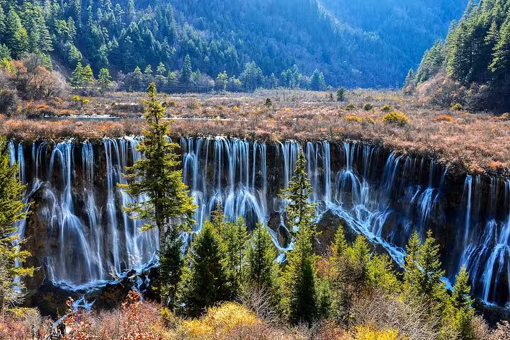 Majestic waterfalls cascading through lush greenery in Jiuzhaigou, highlighting a private three-day rail tour.