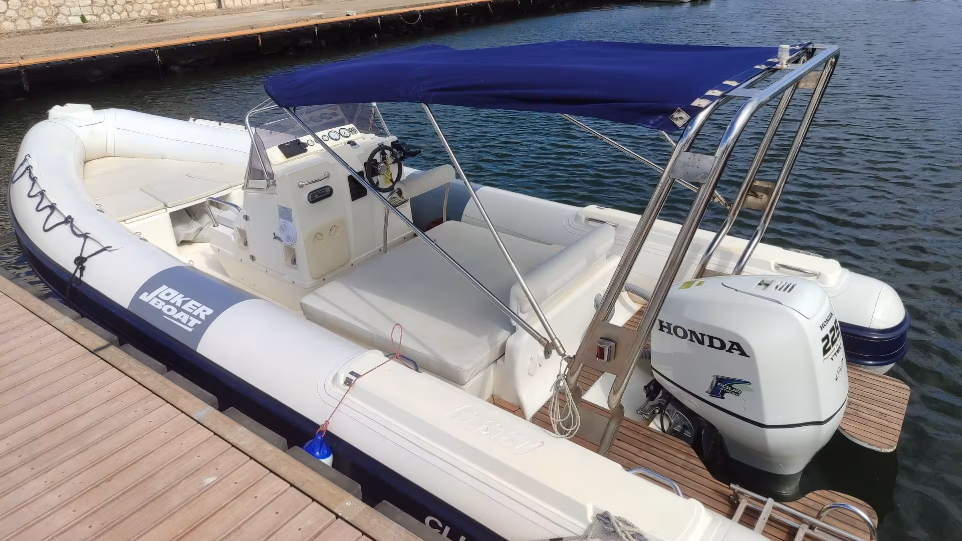 Docked Joker Boat Clubman 24 ready for Cagliari dinghy tour, featuring a spacious seating area and powerful motor.