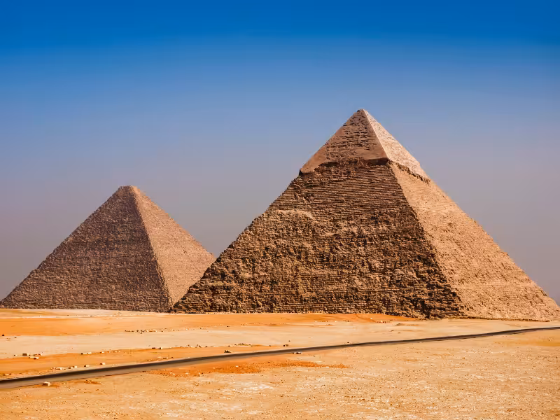 Desert panorama of the Great Pyramids of Giza under blue sky, classic Middle East day trip