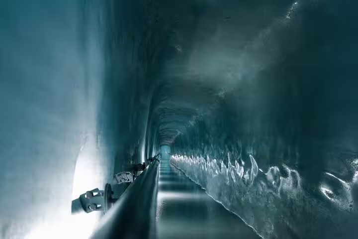 Explore the mesmerizing ice tunnel of Jungfraujoch, featuring illuminated icy walls on a private day trip adventure.