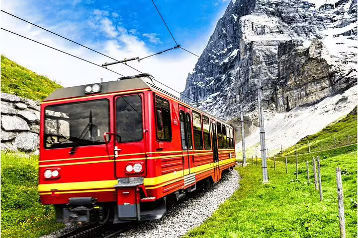 Scenic red train journey through the picturesque Swiss Alps en route to Jungfraujoch on a private day trip.