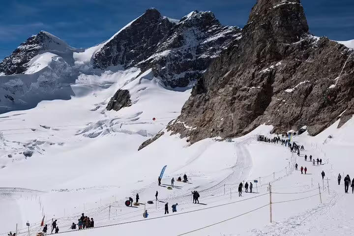 Visitors trekking through snow-covered trails with breathtaking views of Jungfrau peaks on a scenic day trip.
