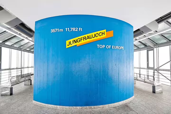 Interior of Jungfraujoch station featuring a blue wall sign marking 3571m elevation, known as the Top of Europe.