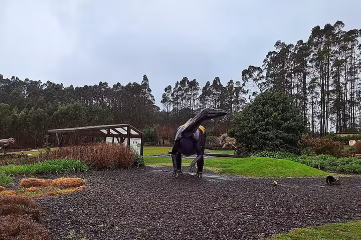 Life-sized dinosaur models in lush garden at Jurassic Museum of Asturias, perfect for family tours from Oviedo.