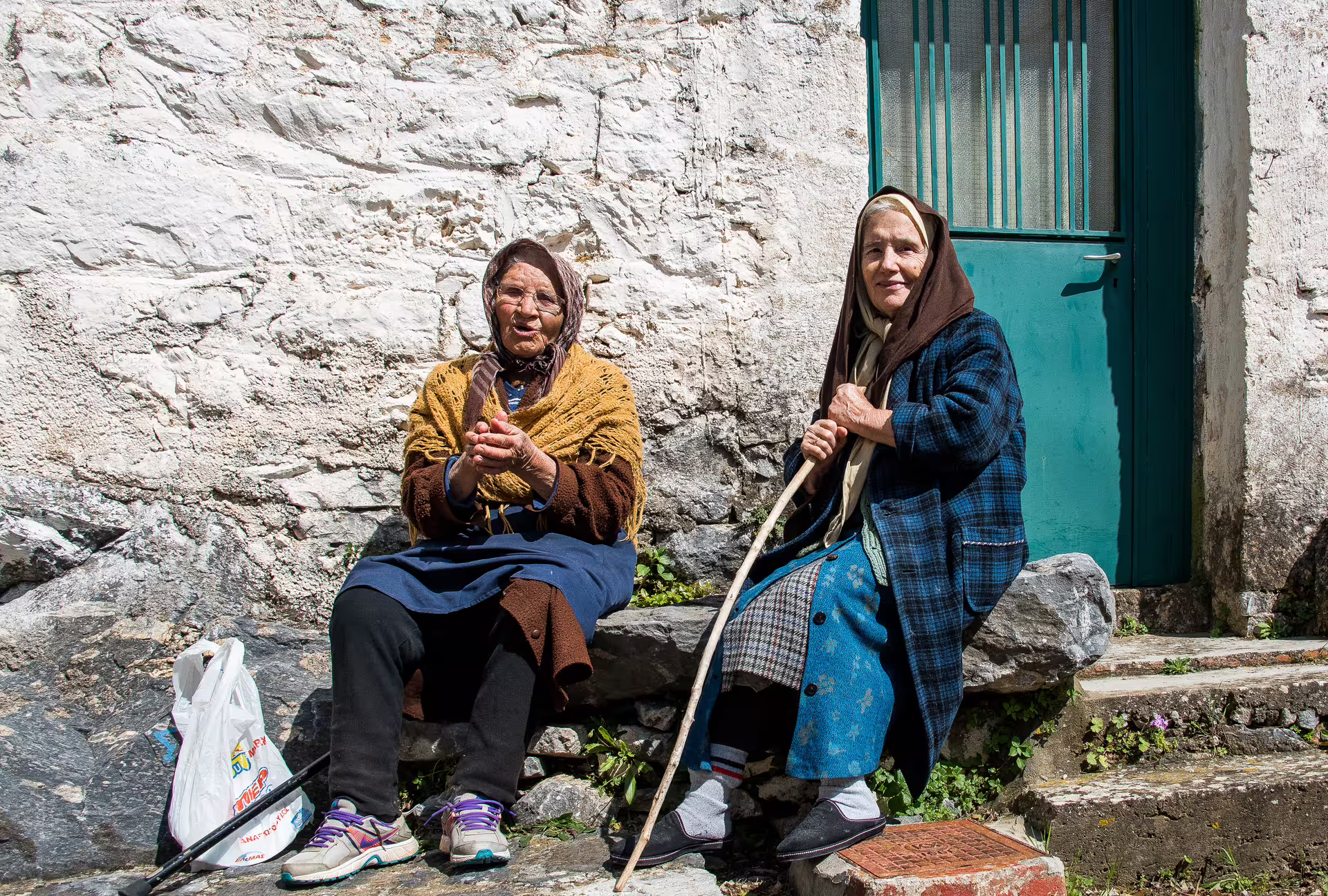 Local village women resting by a stone wall in Mani near Kardamyli, a cultural stop on the hiking tour