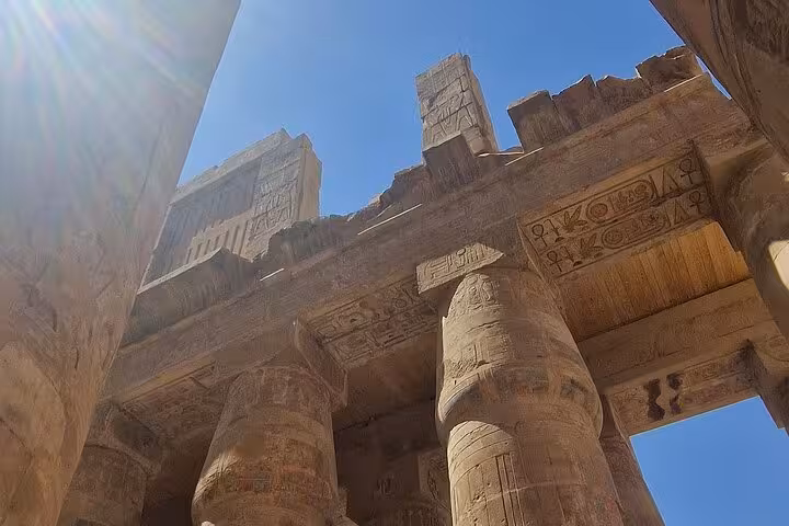 View of ancient columns and hieroglyphics at Karnak Temple under a bright blue sky on a private Luxor tour.