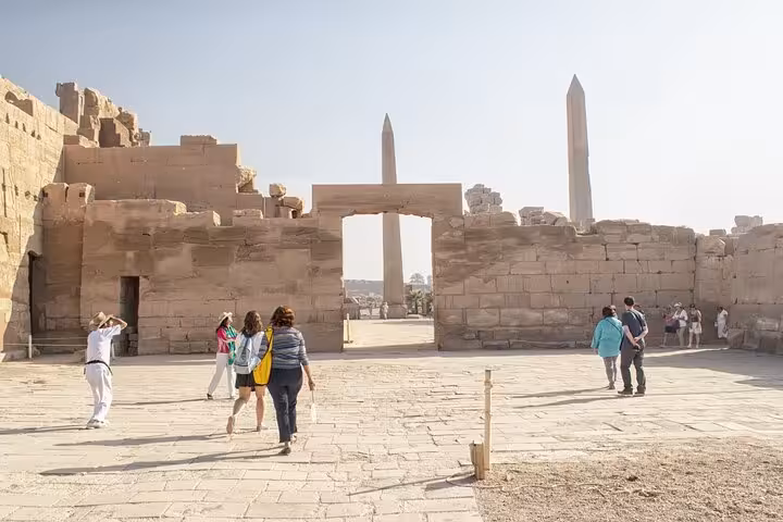 Visitors entering Karnak Temple gateway with obelisks, part of Luxor full-day West and East Bank tour