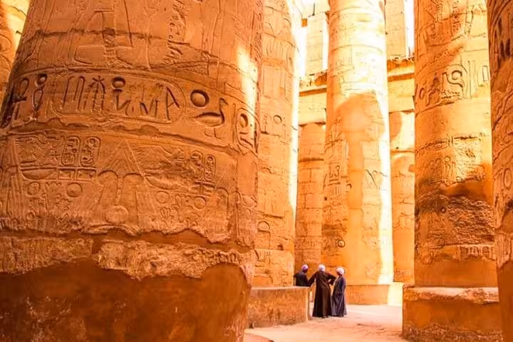 Travelers admiring hieroglyphs inside Karnak Temple columns on Luxor East Bank stop of full-day tour