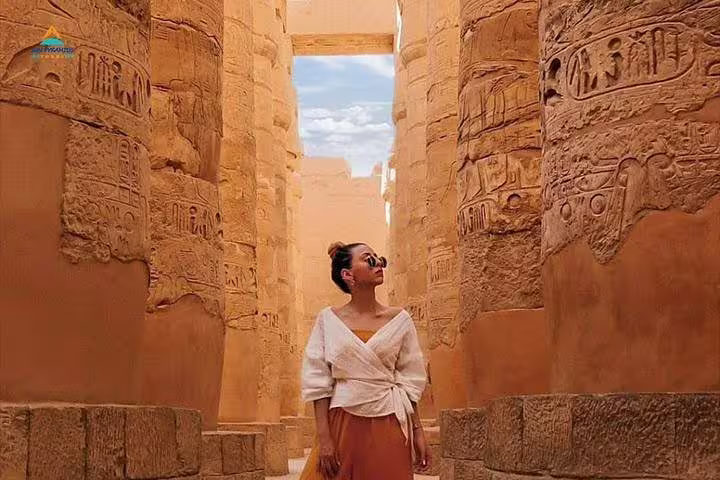 Traveler in Karnak Temple corridor with ancient hieroglyphs, Luxor East Bank guided tour Egypt