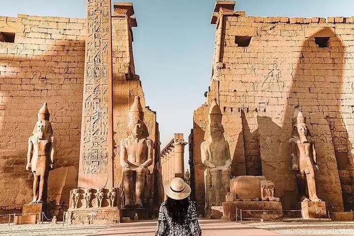 Visitor facing Karnak Temple avenue and obelisk on Luxor East Bank Nile tour, Egypt pharaoh statues and hieroglyphs