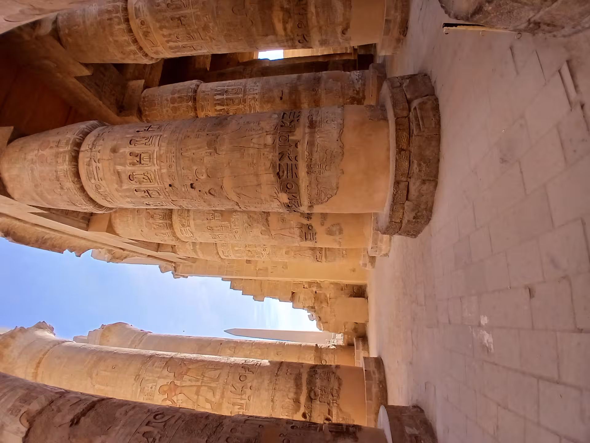 Explore the grand columns of Karnak Temple in Luxor, showcasing ancient Egyptian hieroglyphs under the clear blue sky.