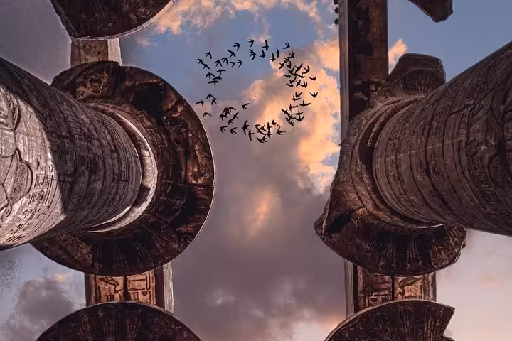 Karnak Temple columns in Luxor at sunset with birds overhead, iconic sight on 7-day private Egypt tour