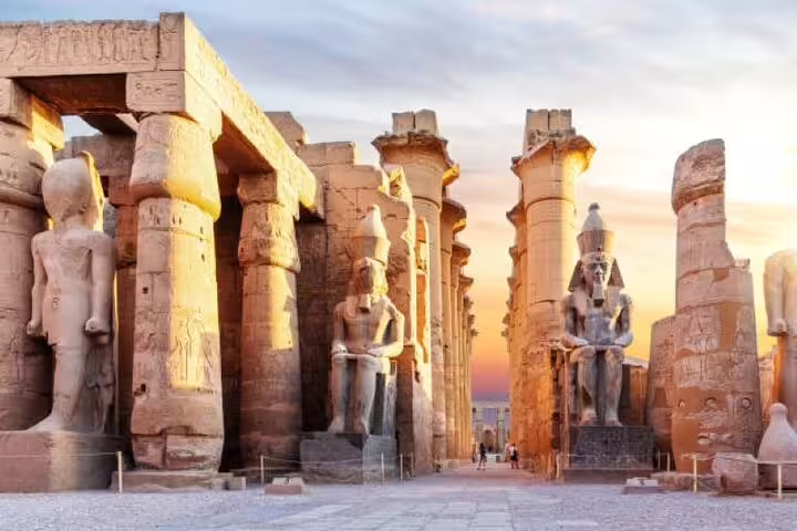 Karnak Temple Luxor at sunset with colossal pharaoh statues and towering columns on a guided day tour