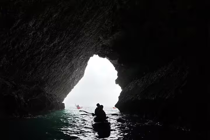 Kayakers explore a stunning sea cave in Sesimbra, highlighting the natural beauty of Arrábida Natural Park's coastal adventures.