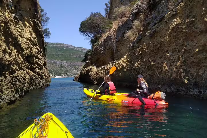 Kayakers navigating through narrow cliffs in a scenic coastal area near Lisbon on a sunny day.