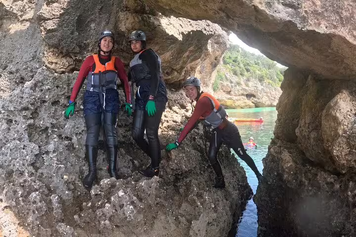 Adventurers explore rugged coastal cliffs while coasteering near Lisbon, perfect for a thrilling full-day adventure tour.