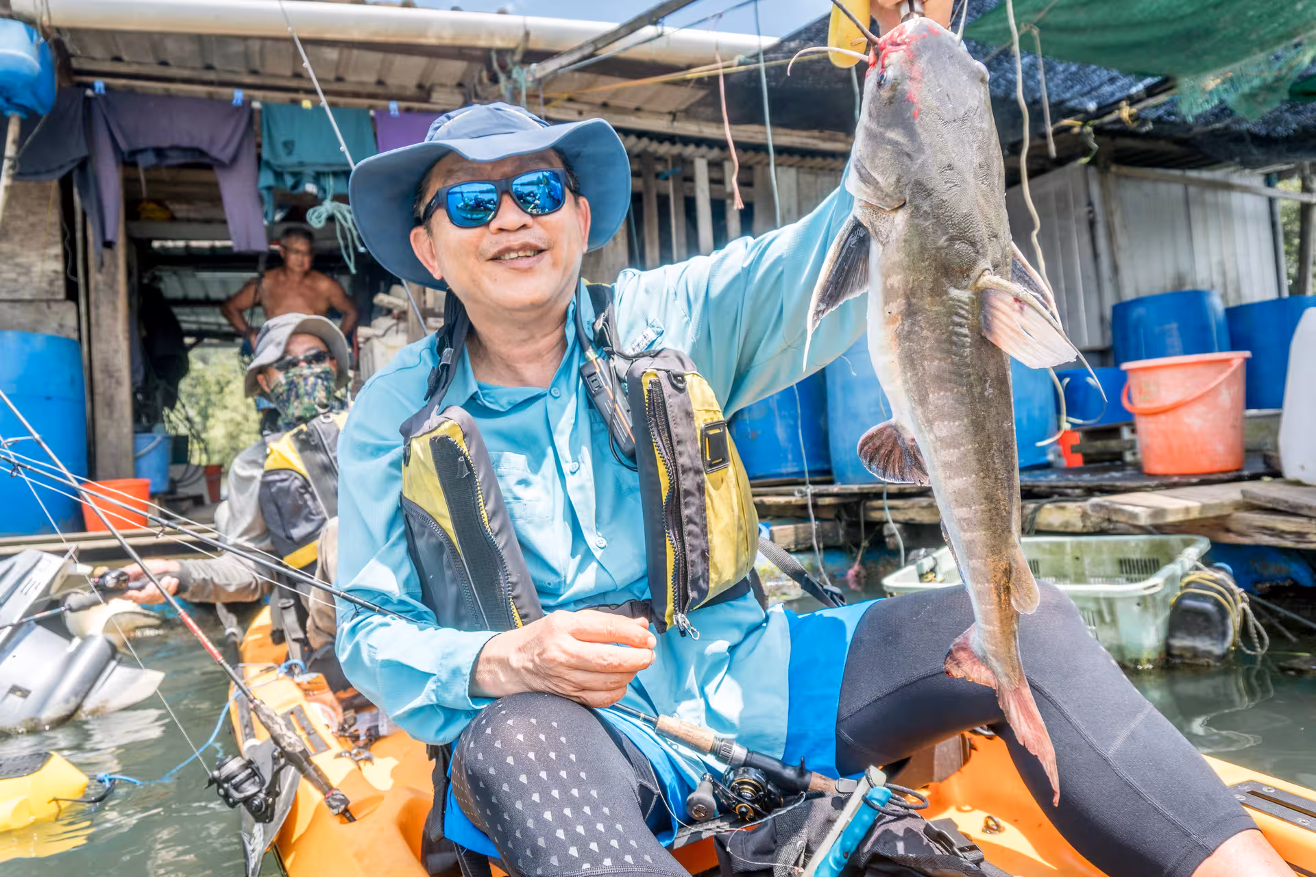 Joyful angler shows off impressive catch while kayak fishing near kelongs at Pulau Ubin.