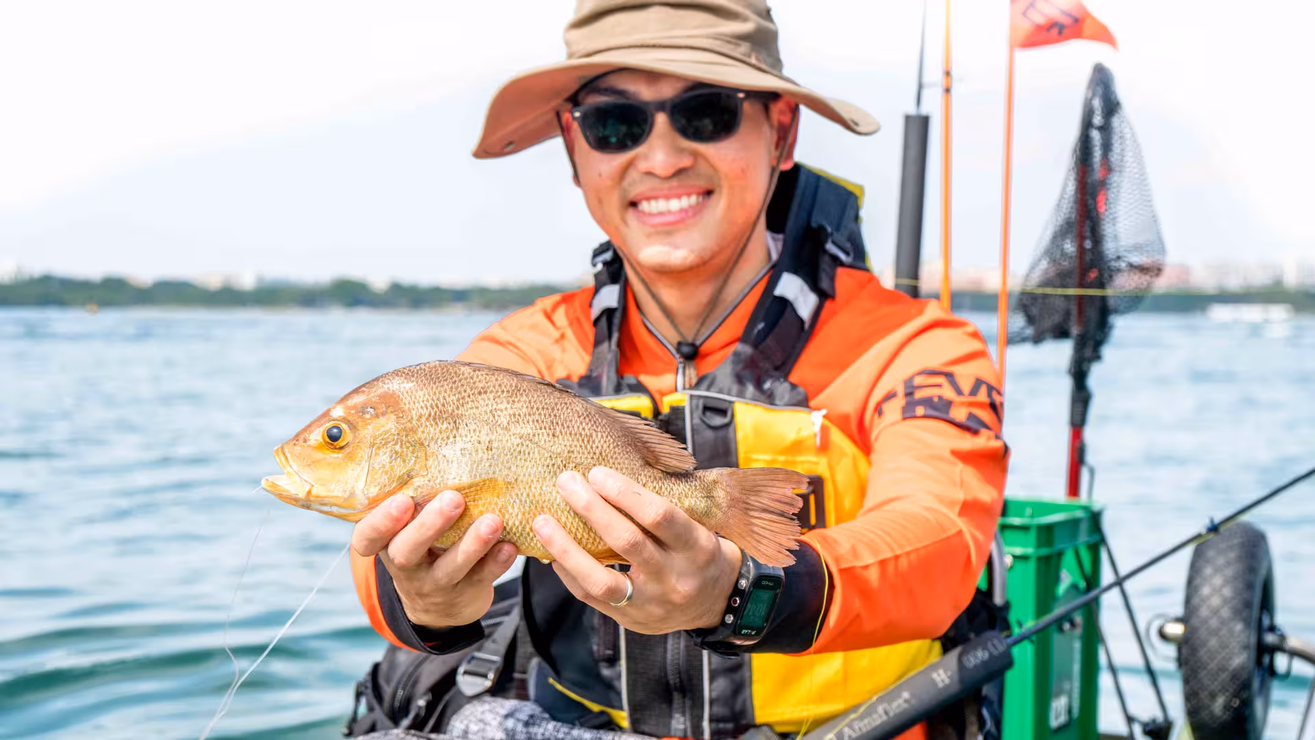 Smiling kayaker proudly holds fresh catch during kayak fishing tour at Pulau Ubin mangroves.