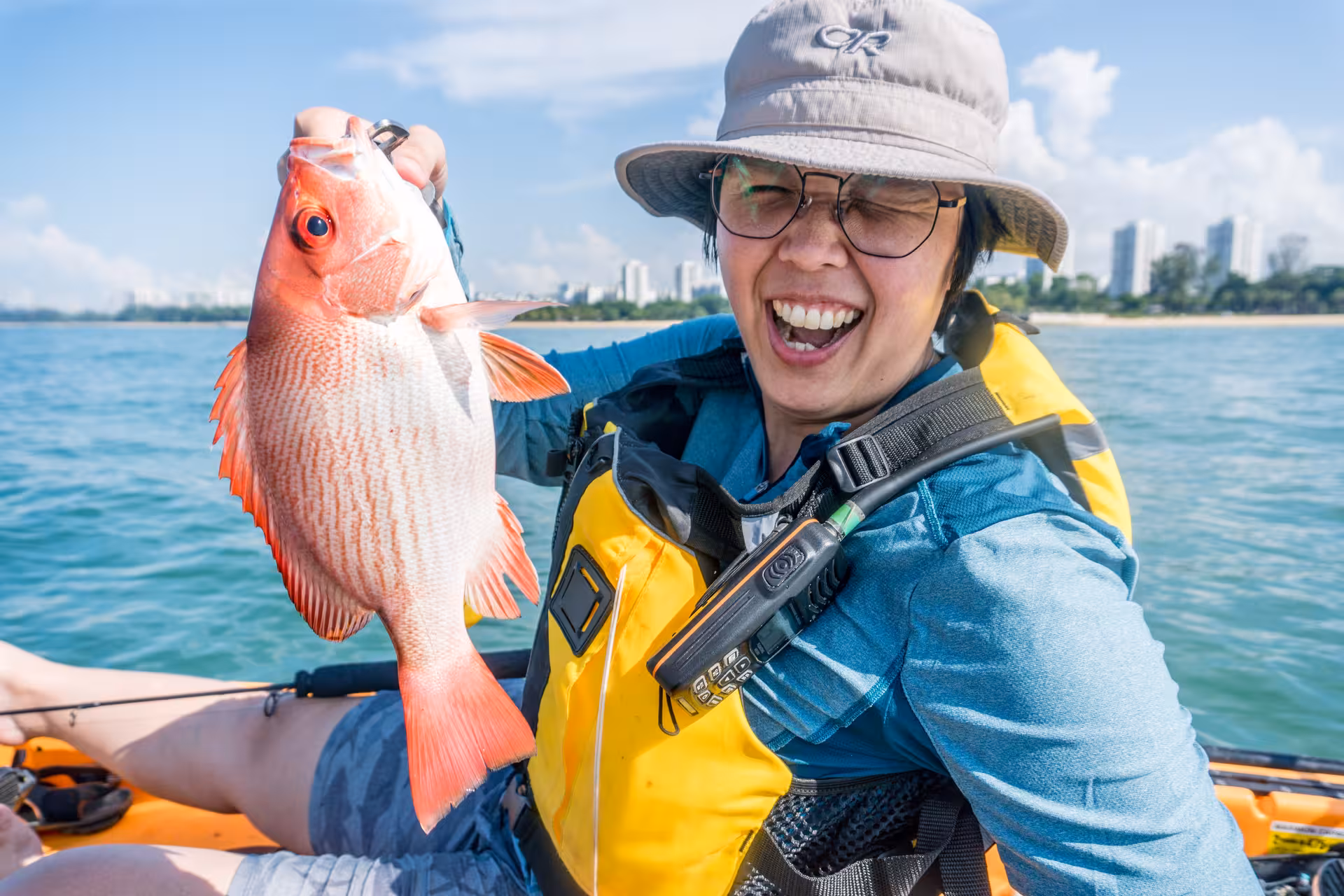 Smiling kayaker proudly displays a red snapper catch during East Coast kayak fishing adventure.
