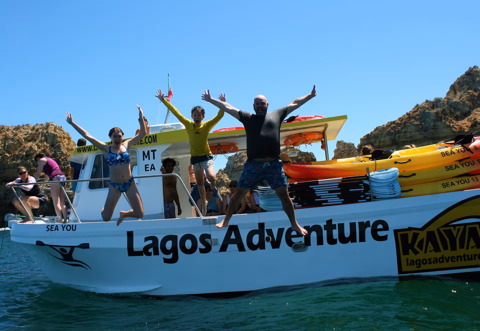 Happy Kayak Lagos Adventure group jumps from Lagos Adventure boat into clear Algarve sea near dramatic cliffs
