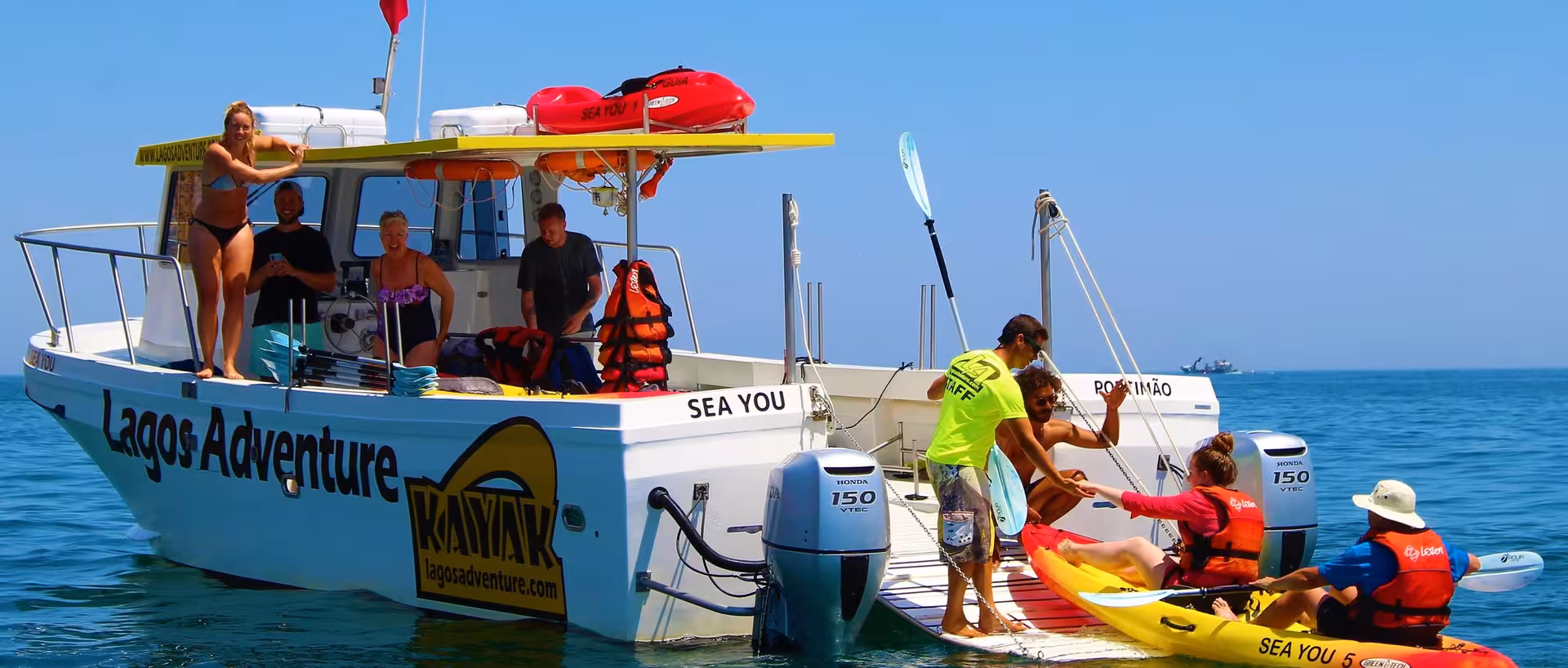 Guided Kayak Lagos Adventure guests board bright yellow kayaks from support boat in calm Algarve ocean waters