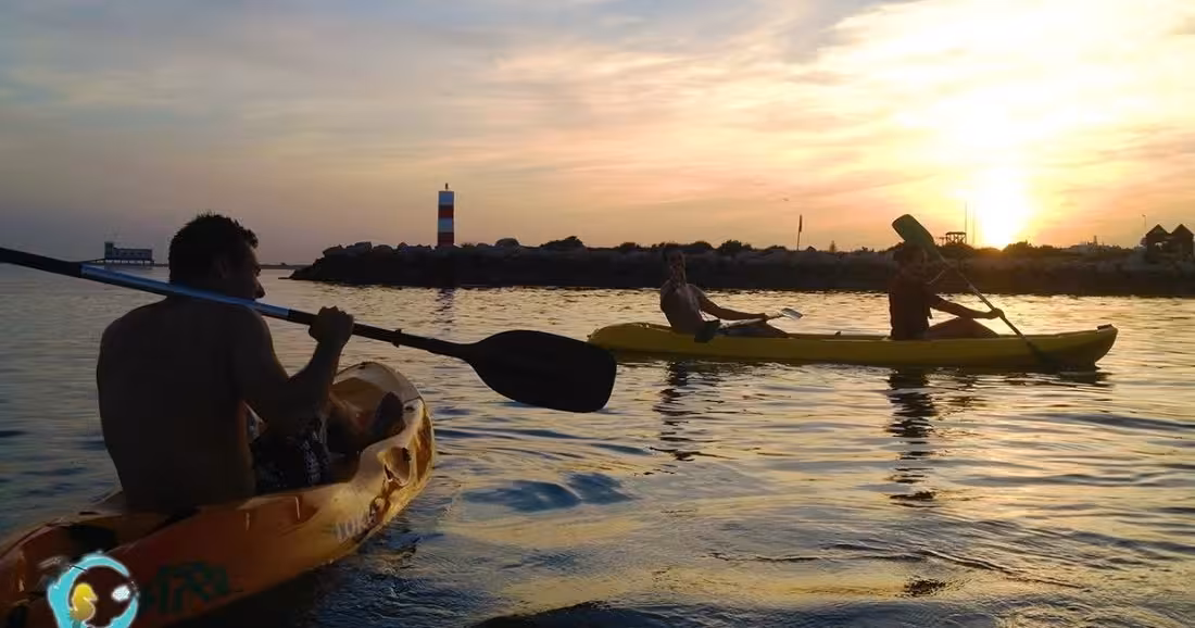 Kayakers paddling at sunset near a lighthouse, perfect for a 4-hour kayak rental and evening water adventure