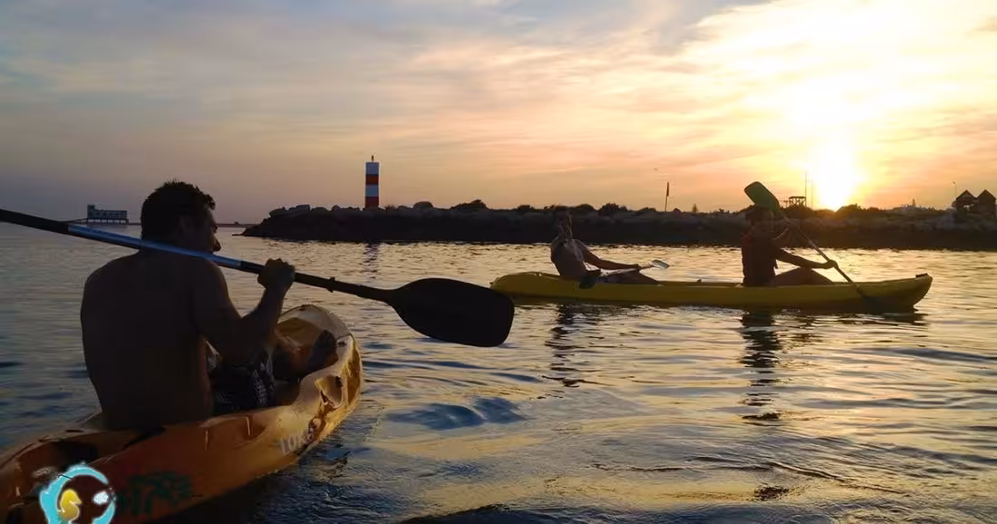 Kayakers paddling at sunset near a lighthouse on calm water during a 2-hour kayak rental adventure