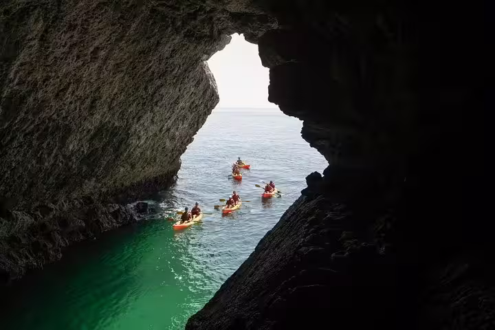 Kayakers explore sea caves in Sesimbra's Arrábida Natural Park, showcasing adventure and stunning coastal scenery.