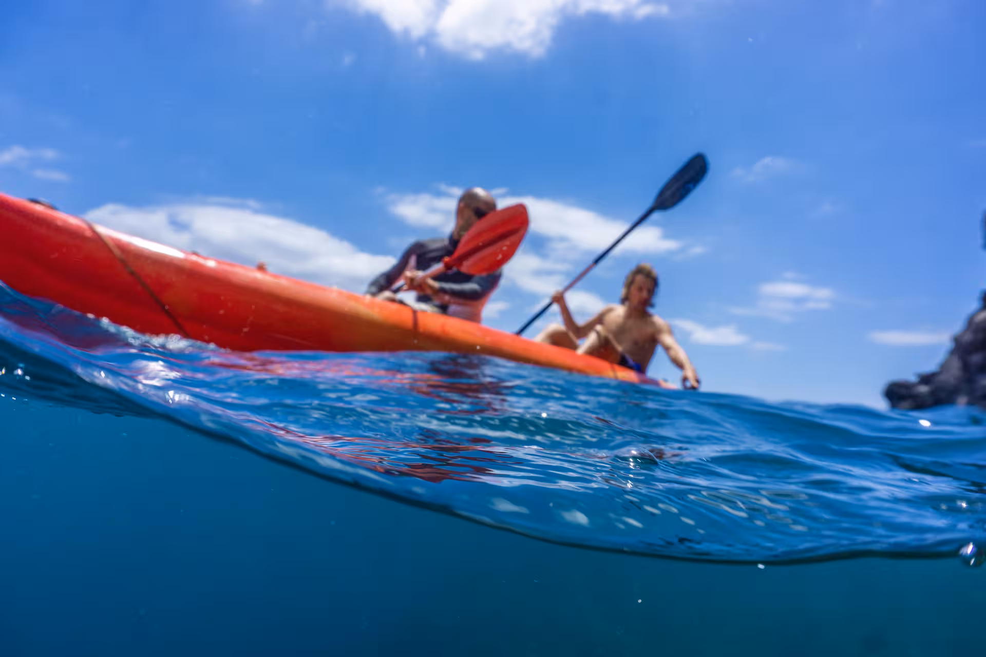 Adventurous kayaking and snorkeling tour with two paddlers exploring clear blue waters under a sunny sky.
